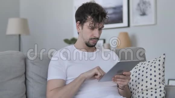 休闲青年男子在桌上的触摸和浏览互联网上放松视频的预览图