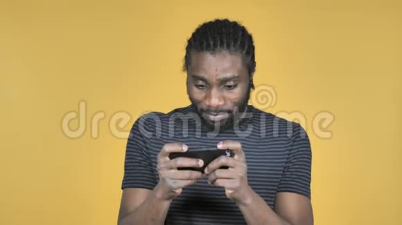 黄色背景下智能手机游戏中的非洲男子视频的预览图