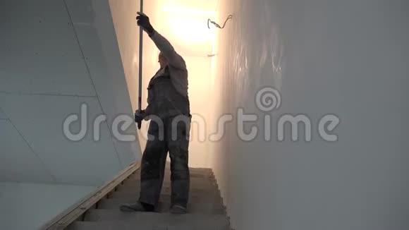 新房楼梯用滚刀油漆顶棚的业余男子视频的预览图
