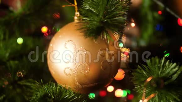 特写4k视频金色闪闪发光的宝珠挂在圣诞树上与五颜六色的闪烁和发光的灯光和视频的预览图