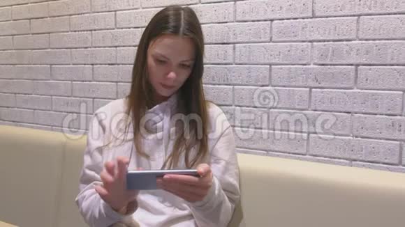 女人正在看手机上的视频坐在咖啡馆里等人视频的预览图