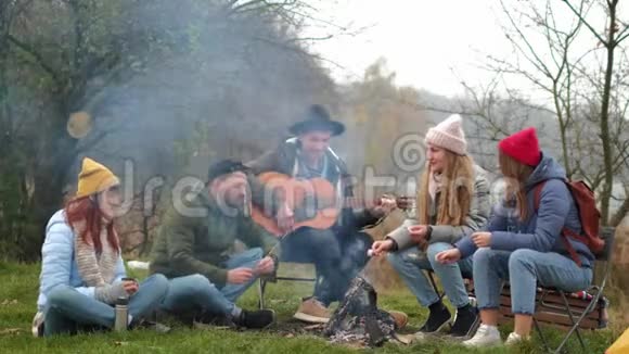 一群朋友露营他们坐在篝火旁弹吉他视频的预览图