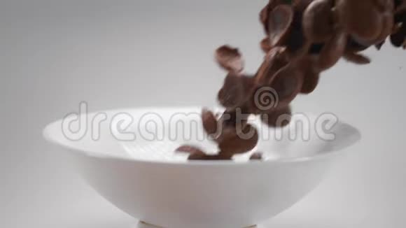 巧克力玉米片正在缓慢地飘落到白色的碗里可可麦片早餐在240英尺长的时间里落下慢的食物视频的预览图