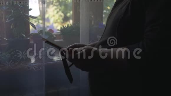 一位老年妇女的特写肖像站在窗口拿着一个相框和你的照片看着它视频的预览图