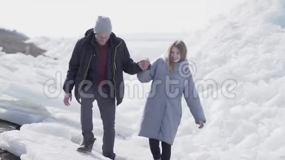 英俊的长胡子男人和漂亮的女人牵着手走着那家伙帮他的女朋友爬上了冰块视频的预览图