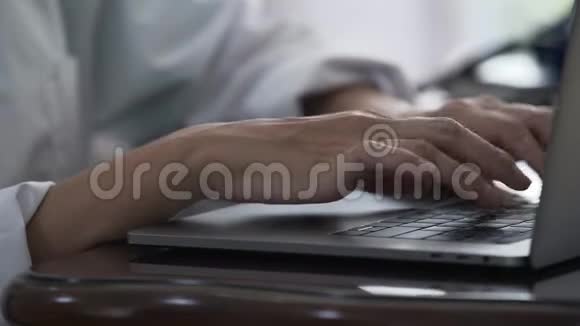 女医生坐在办公室的一张桌子旁用笔记本电脑打字视频的预览图