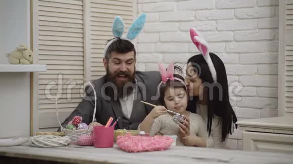 母亲父亲和女儿正在画复活节彩蛋幸福的家庭正在为复活节做准备可爱的小女孩视频的预览图