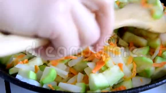 成熟的女人在厨房做饭蔬菜在锅里炒洋葱西葫芦胡萝卜视频的预览图