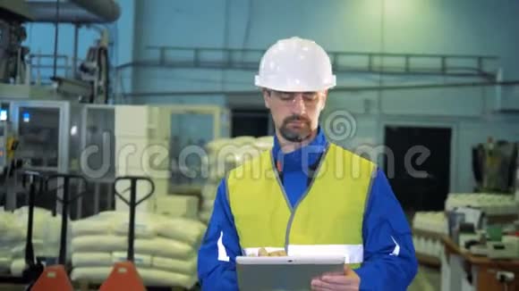 一位带着平板电脑的男性专家正在工厂里散步视频的预览图
