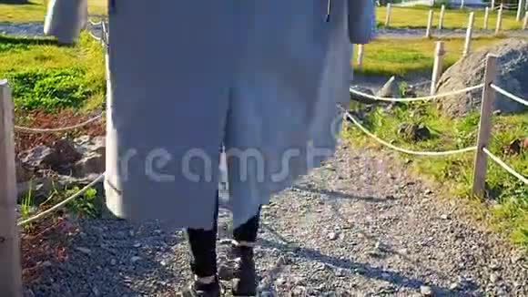 一个穿灰色外套的少女在阳光明媚的日子里穿过公园下山视频的预览图