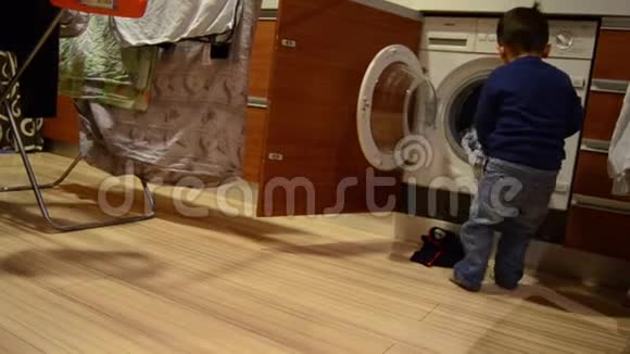 可爱的两岁男孩从洗衣机里拿出洗过的衣服送给妈妈视频的预览图