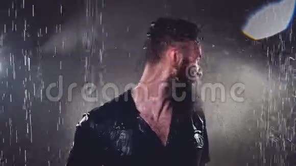 漂亮的年轻人穿着黑色湿衣服在雨和水中飞溅视频的预览图