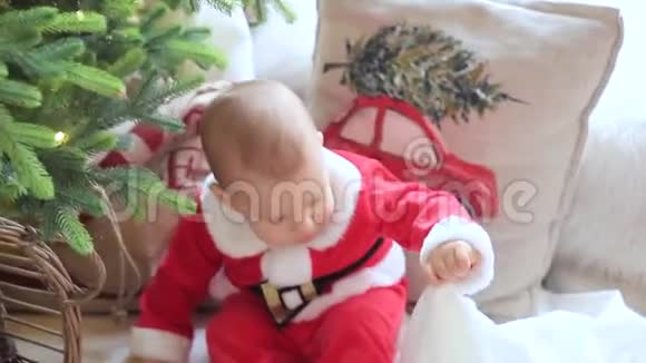 小宝宝坐在地板上坐在一棵装饰好的圣诞树前的房间里视频的预览图