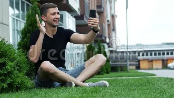 年轻人通过手机视频聊天坐在草地上和朋友说话视频的预览图