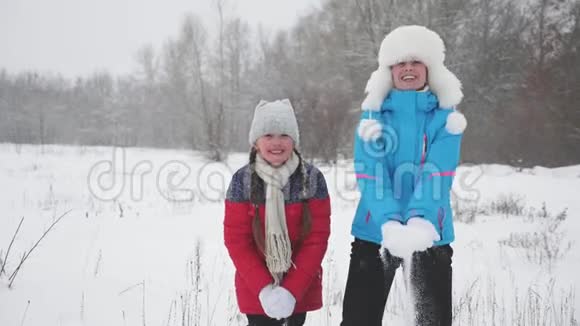 快乐的母女把雪吐了起来雪落了闪闪发光圣诞节假期家庭在冬季公园玩耍视频的预览图