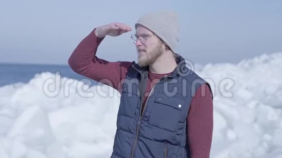 年轻的英俊男子游客集中在寒冷的冰雪冰川后面的冬季海洋慢动作视频的预览图