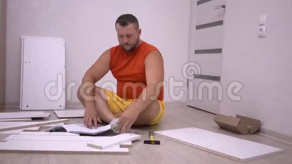 一个长着黄袍胡须的可爱胖乎乎的男人在家里收集家具仔细考虑指令视频的预览图