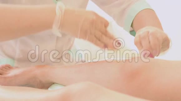 在美容水疗中心为顾客的腿打蜡的女性治疗师特写脱毛腿视频的预览图