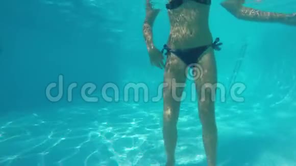穿着蓝色泳衣的白人女孩在镜头前潜水并从她的嘴里吐出泡泡从水下看视频的预览图
