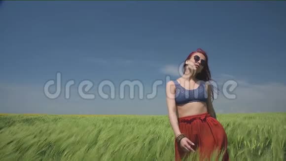年轻女子穿着波霍式的衣服在绿色的麦田中摇曳迎风招展闭上眼睛视频的预览图