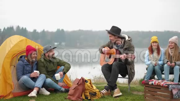 一群朋友露营他们坐在篝火旁弹吉他视频的预览图
