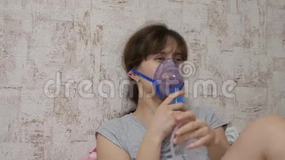 一个生病的女孩被坐在沙发上的喷雾器吸入戴面具的女人吸入呼吸道蒸气视频的预览图