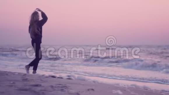 日出时美丽的女孩走在海滨潮湿的沙滩上视频的预览图