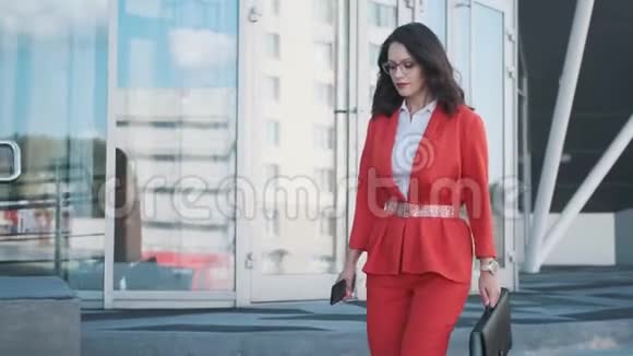穿着正式西装的商务女性走在现代商务中心的背景下视频的预览图