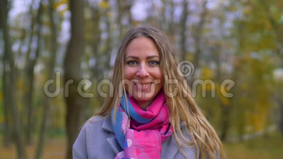 微笑的女人用黄叶遮住她的脸视频的预览图