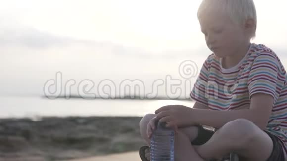 那个男孩在日落时在海边喝水视频的预览图