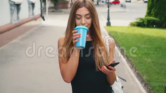 迷人的年轻女性浅棕色的头发走在市中心检查她的智能手机和喝咖啡视频的预览图