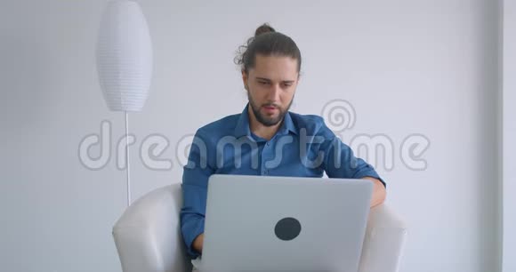 进步的自由职业者马尾辫工作与笔记本电脑坐在扶手椅在舒适和轻的办公室视频的预览图