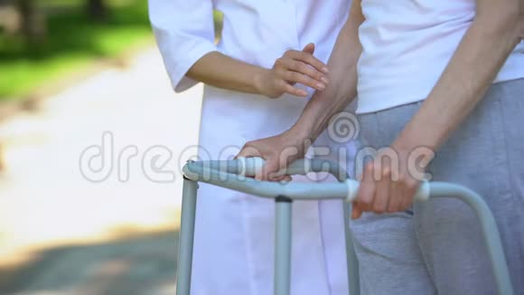 女护士支持残疾老太太户外步行架康复视频的预览图