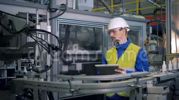一名男性工人正在检查运送塑料容器的机器视频的预览图