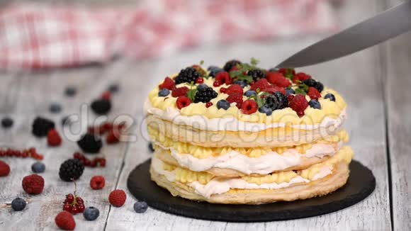 用浆果和薄荷装饰在桌子上的分层蛋糕女人切美味的泡芙糕点蛋糕视频的预览图