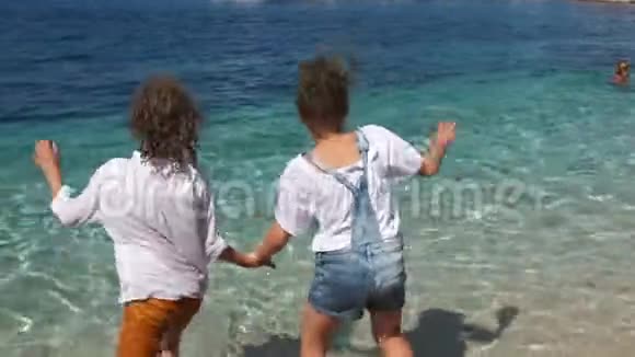 一对漂亮的孩子一个男孩和一个女孩穿着衣服进入水中孩子们快乐和孩子们一起度假视频的预览图