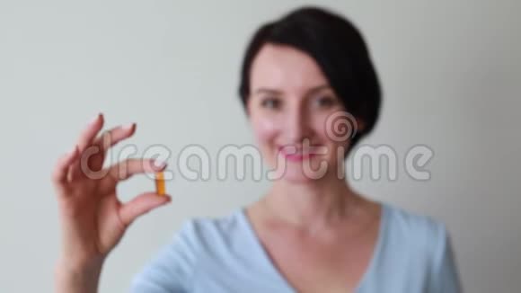 年轻微笑的女性拿着药丸视频的预览图