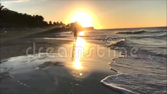 一个小男孩在沙滩上对着相机在日落时慢镜头的片段视频的预览图