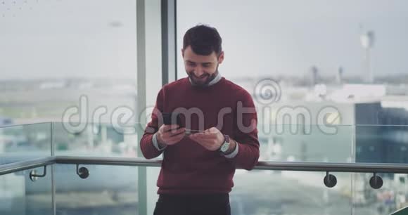在现代建筑中快乐的上班族使用智能手机和银行卡在线检查他的银行账户最后是视频的预览图