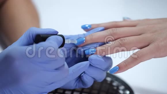 为客户做蓝色美甲的美容师双手特写视频的预览图
