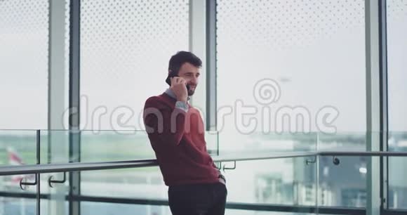 机场里充满魅力的年轻经理在他的智能手机上交谈直到他等待他的飞行视频的预览图