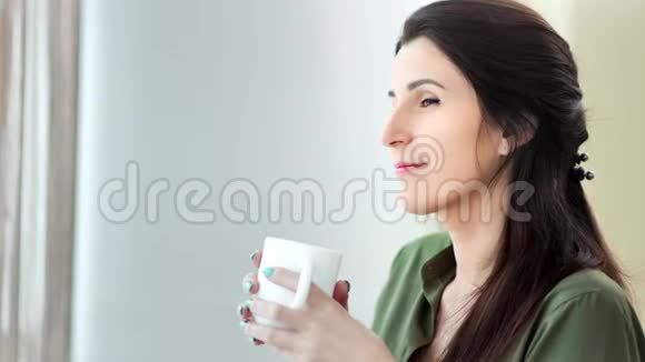中度特写微笑的女人梦想着喝白大杯子里的热饮料视频的预览图