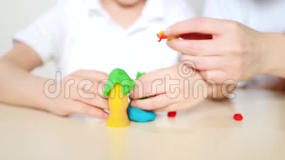 快乐的妈妈和孩子一起玩塑料面团混合模型特写视频的预览图