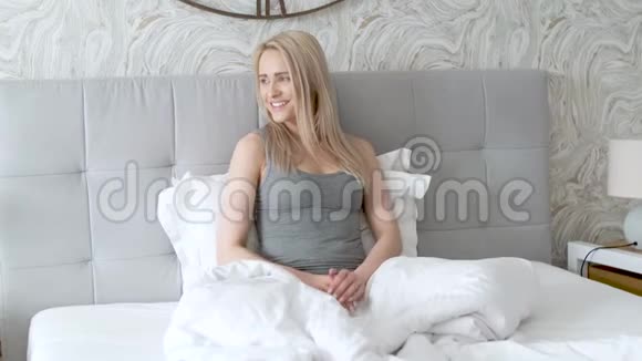 快乐的年轻女子在床上享受阳光明媚的早晨视频的预览图