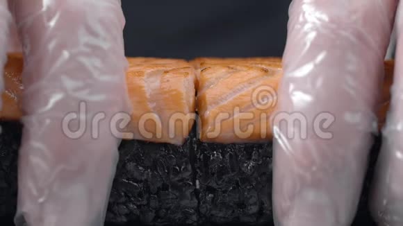 厨师用黑米和三文鱼把寿司卷分成一半煮生的红鱼脆三文鱼寿司卷视频的预览图