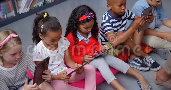 混合种族学童在学校图书馆4k学习数码平板电脑的高视角视频的预览图