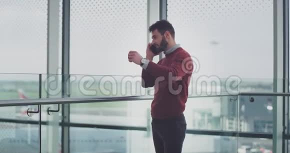 商人在机场等他的飞机他打电话给某人说话最后他检查了他手上的时间视频的预览图