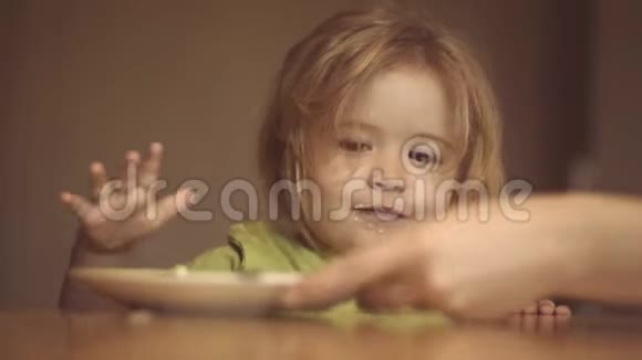 快乐的婴儿用勺子吃食物美丽的孩子在家吃早餐的肖像微笑快乐视频的预览图