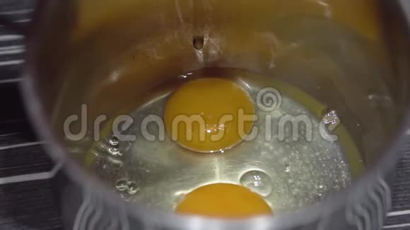 女人的手在碗里砸鸡蛋在厨房打碎一个鸡蛋慢动作视频的预览图