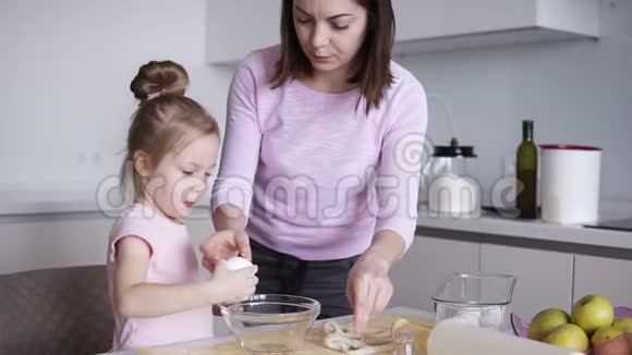母女俩在厨房一起做饭小女孩在碗里打碎鸡蛋幸福家庭烘焙糕点视频的预览图